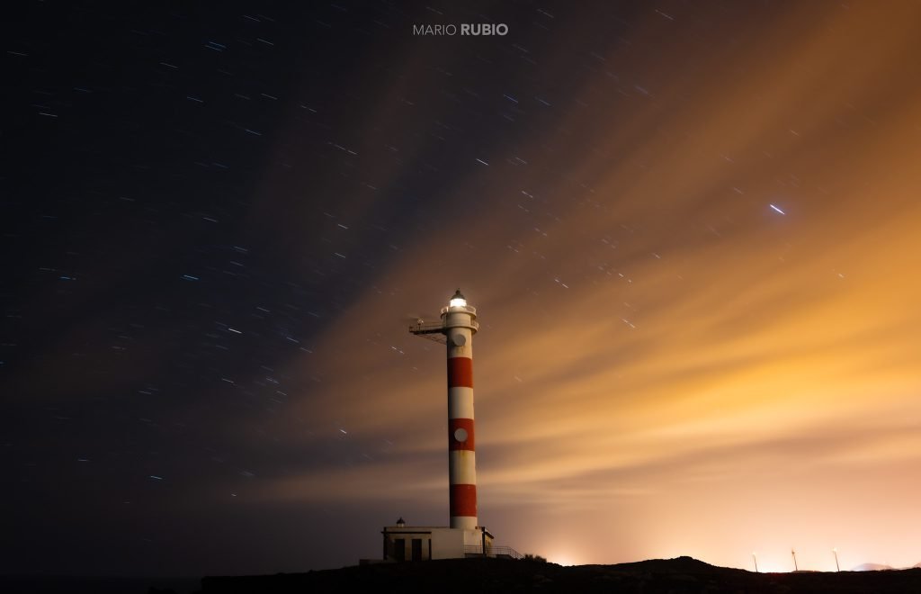 Faro de Tenerife bajo estrellas y nubes iluminadas