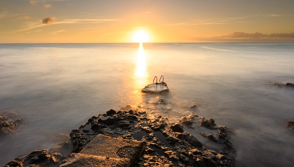 Piscina natural volcánica frente al océano al atardecer